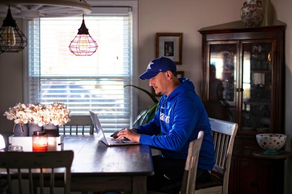 Man on a laptop in his dining room.